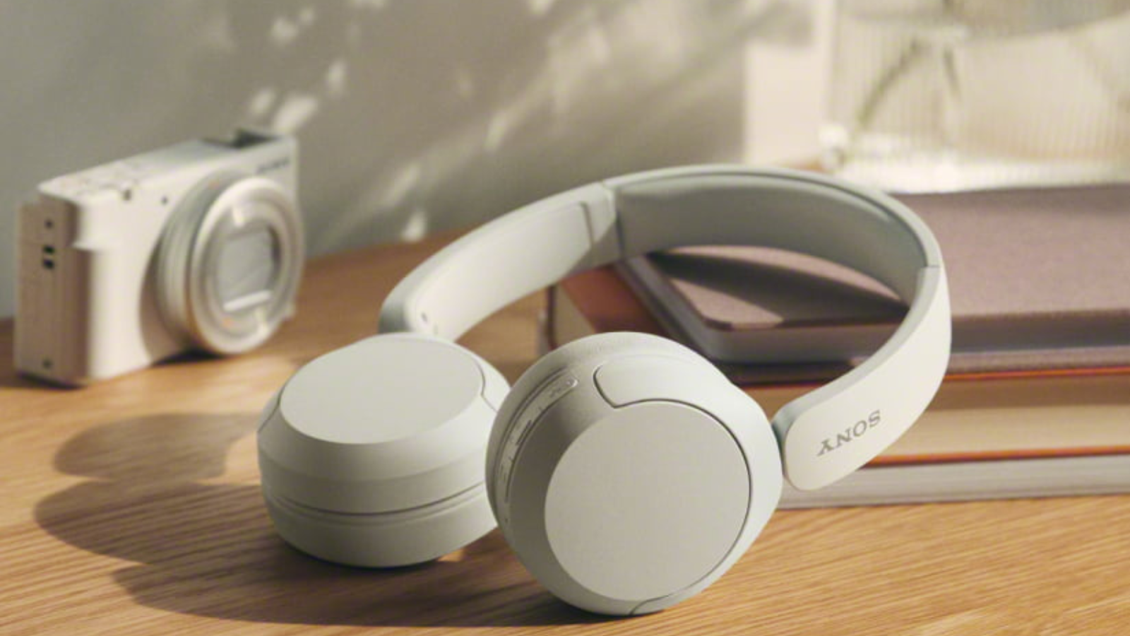 white Sony WH-CH520 headphones laying on table with books and camera