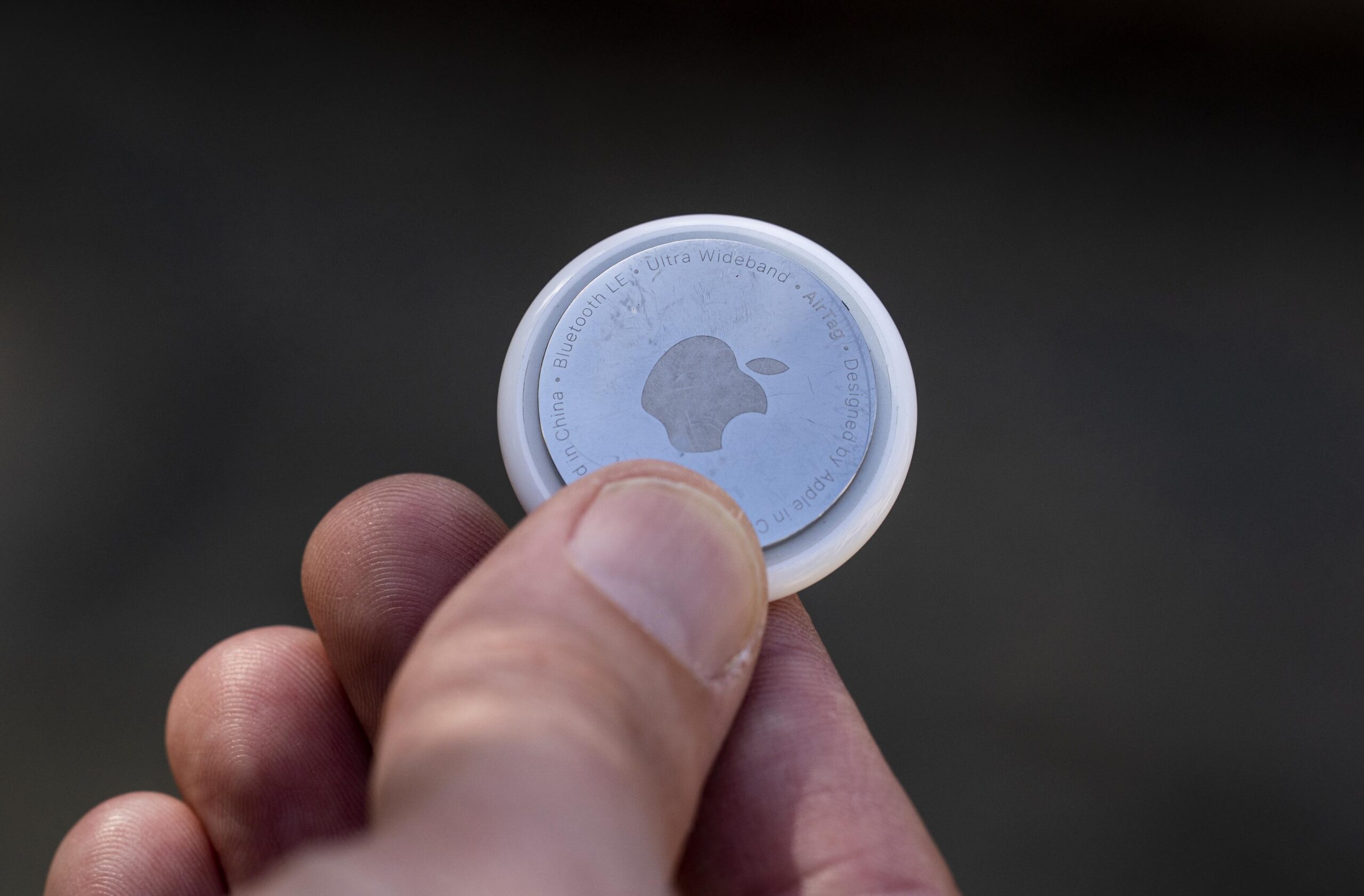 An Apple AirTag held in a person's hand.