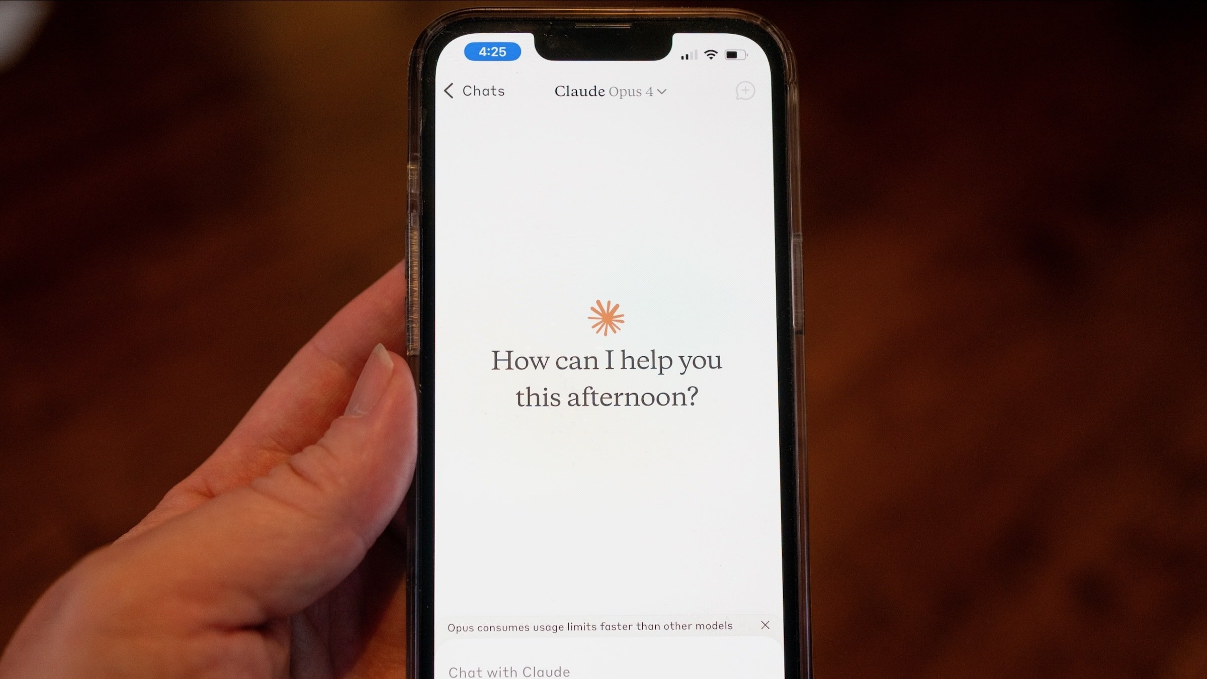 Close-up of a person's hand holding a smartphone and using the claude Opus 4 model 