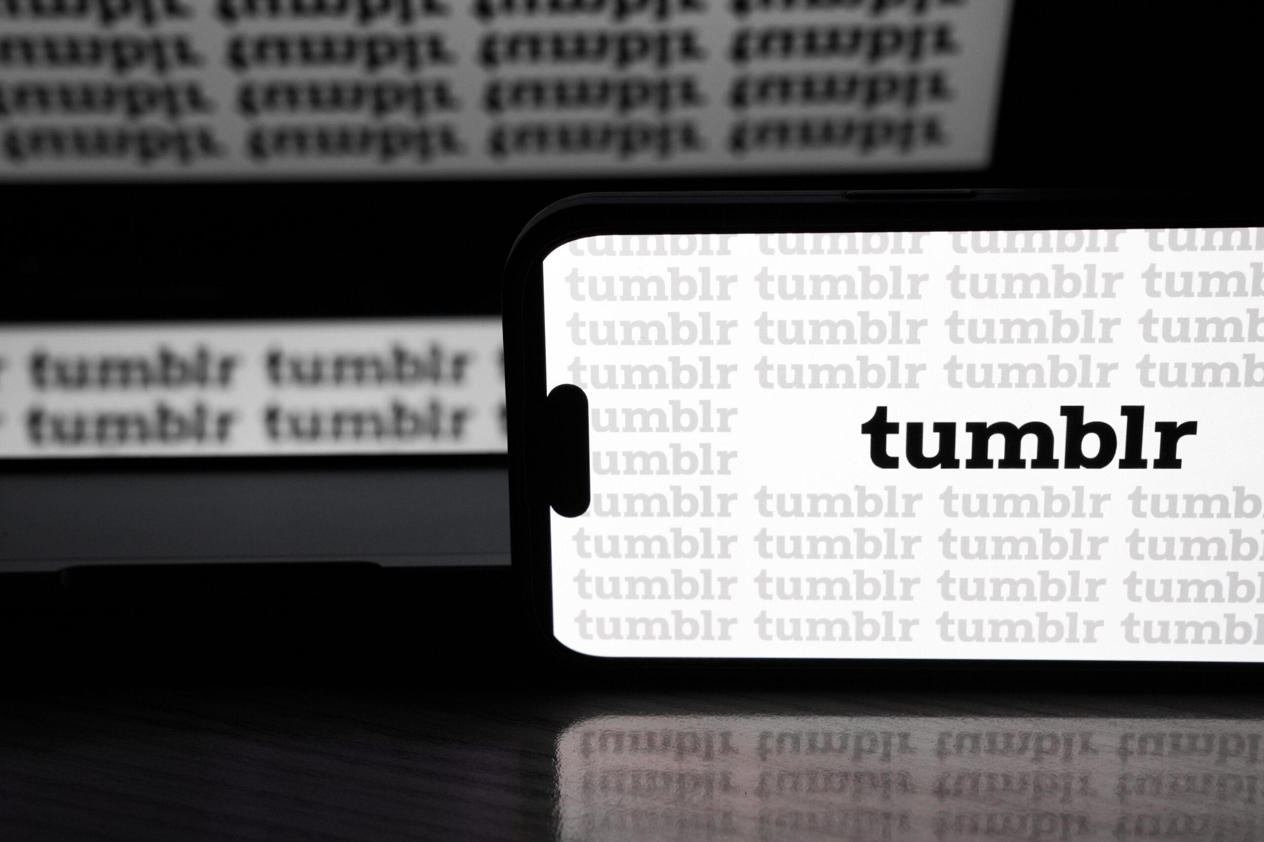 the tumblr logo all over a phone and screen behind the phone