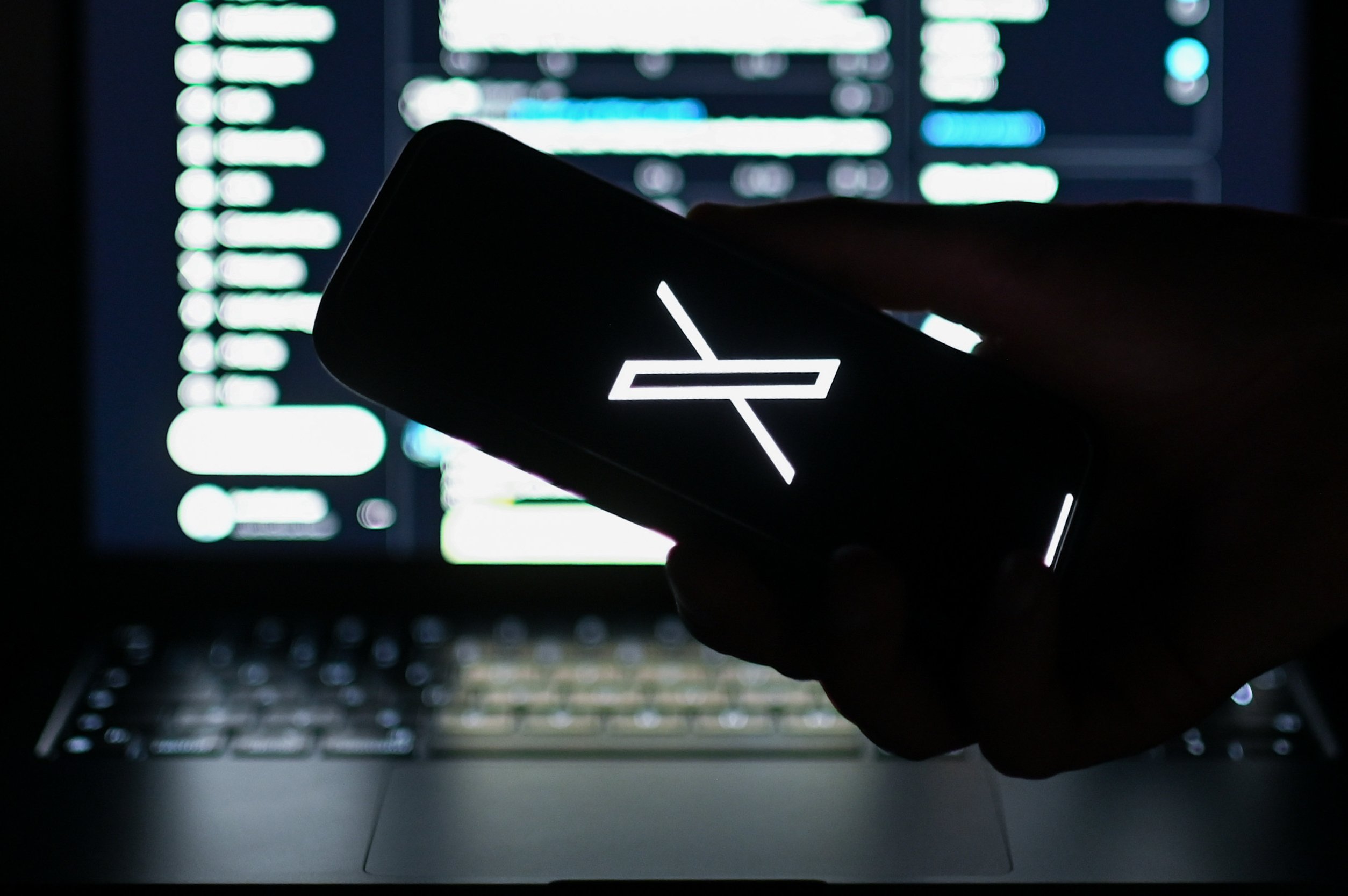 X logo in front of laptop