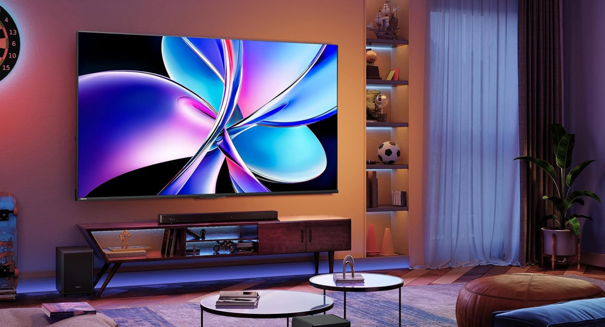 A large Hisense TV mounted on the wall of a stylish, dimly lit living room. Below it, a media console with a soundbar is illuminated by purple ambient light. The TV screen displays a vibrant, abstract swirl of colors.