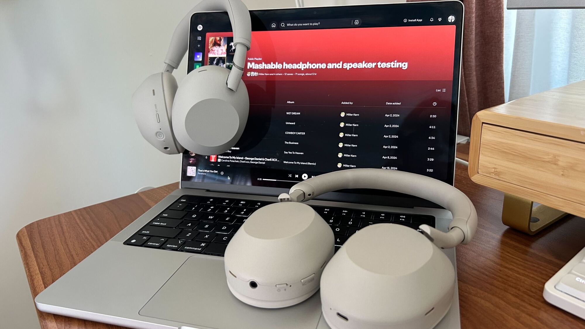 two pairs of sony headphones on macbook with spotify playlist open