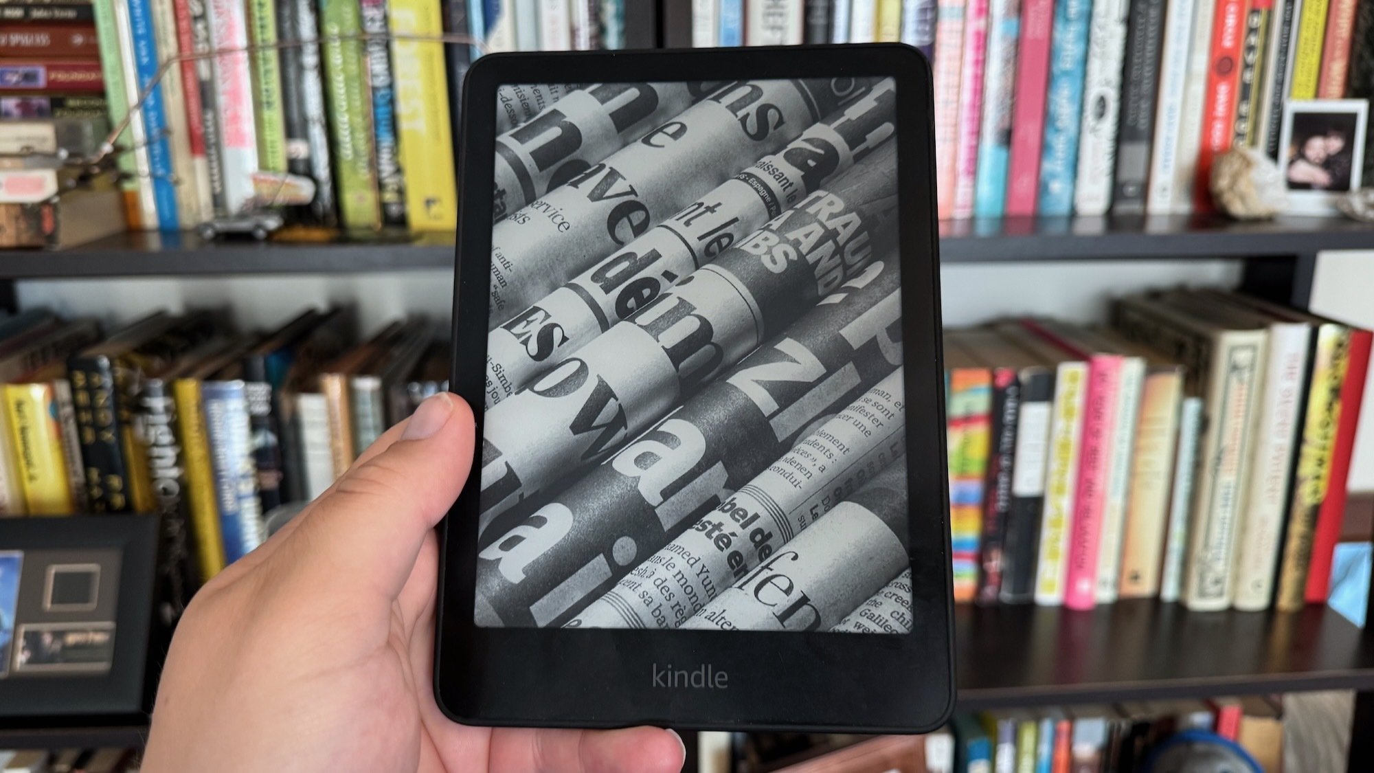 kindle paperwhite held up in front of bookshelf
