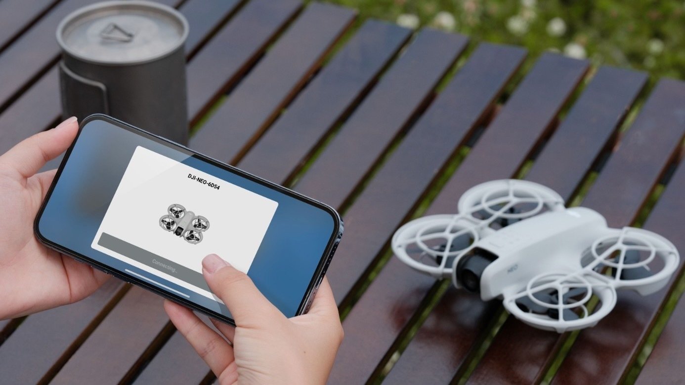 a dji neo on a table with someone controlling it by phone