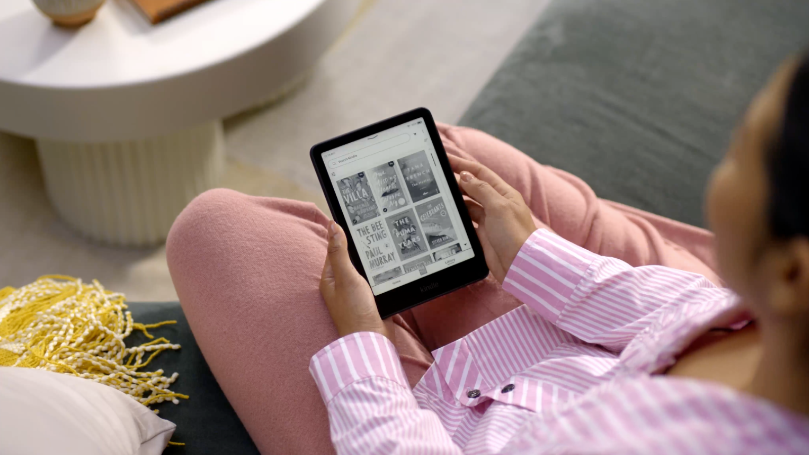 woman sitting on couch looking at Kindle Paperwhite screen
