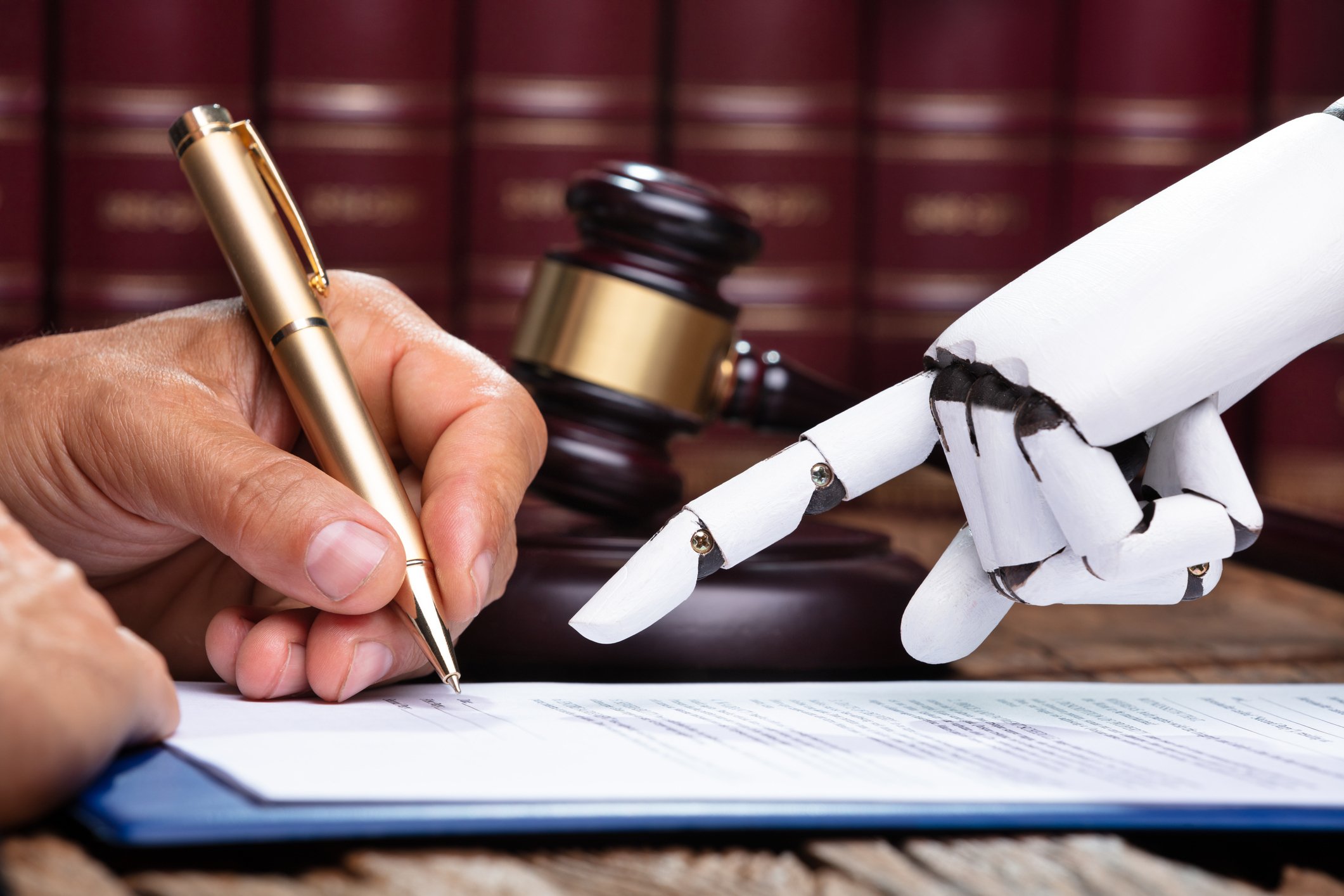 A robotic hand pointing to a human hand signing a document.