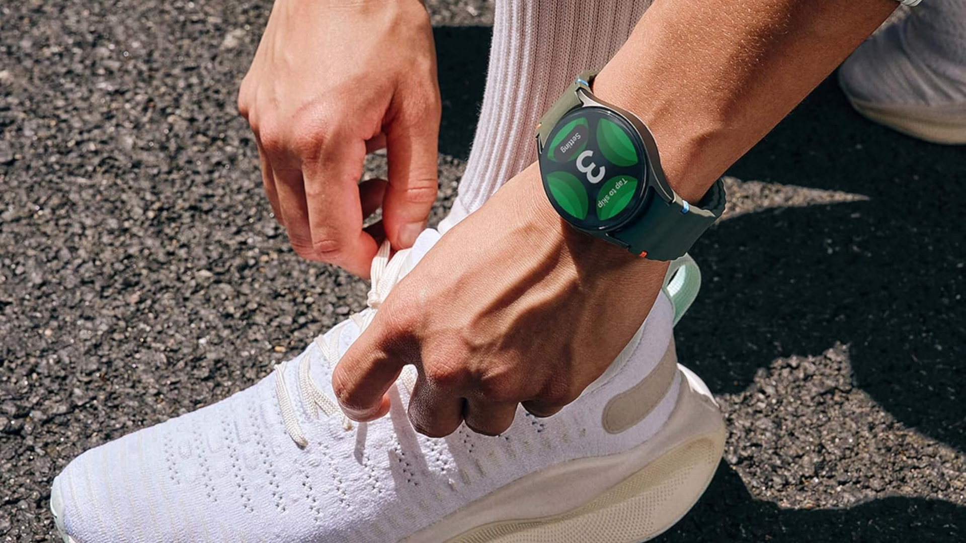 A person wearing a Samsung Galaxy Watch on their wrist while adjusting their sneaker.