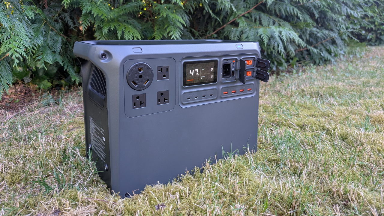 the DJI power 2000 portable power station sits in grass with a large green tree in the background