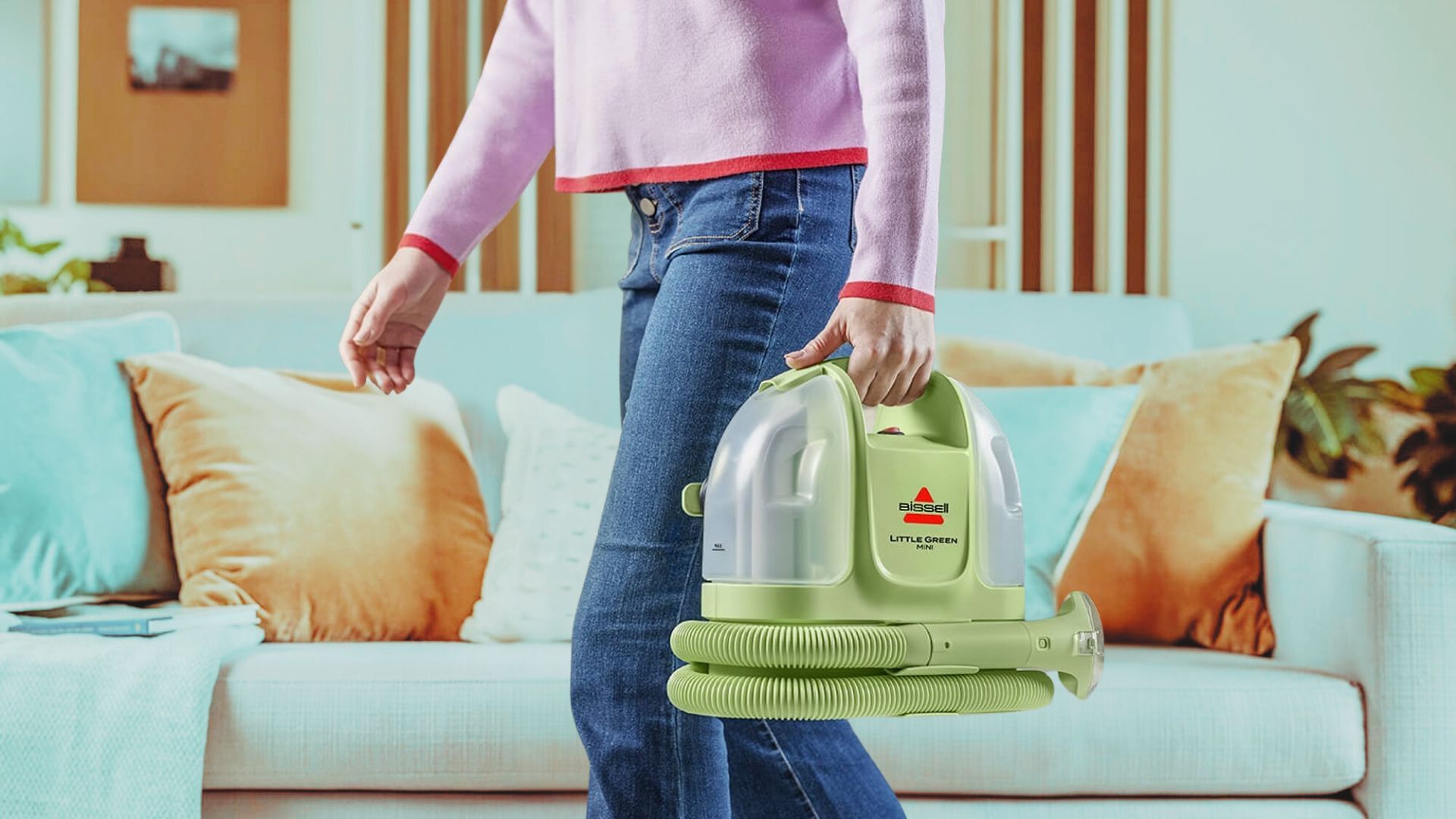 woman carrying bissell little green mini through living room