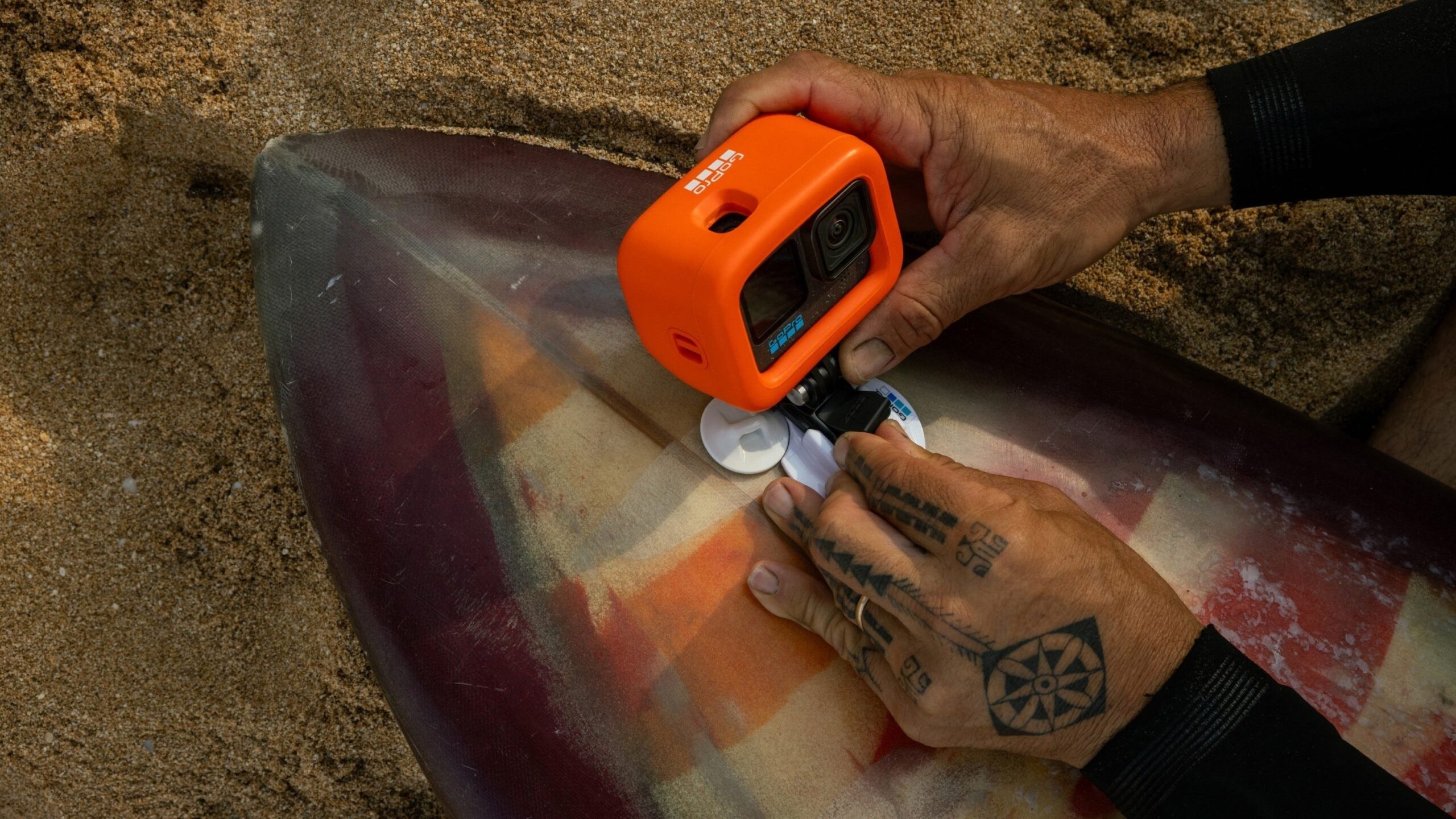 a person mounts the GoPro Hero12 Black action camera to a surfboard