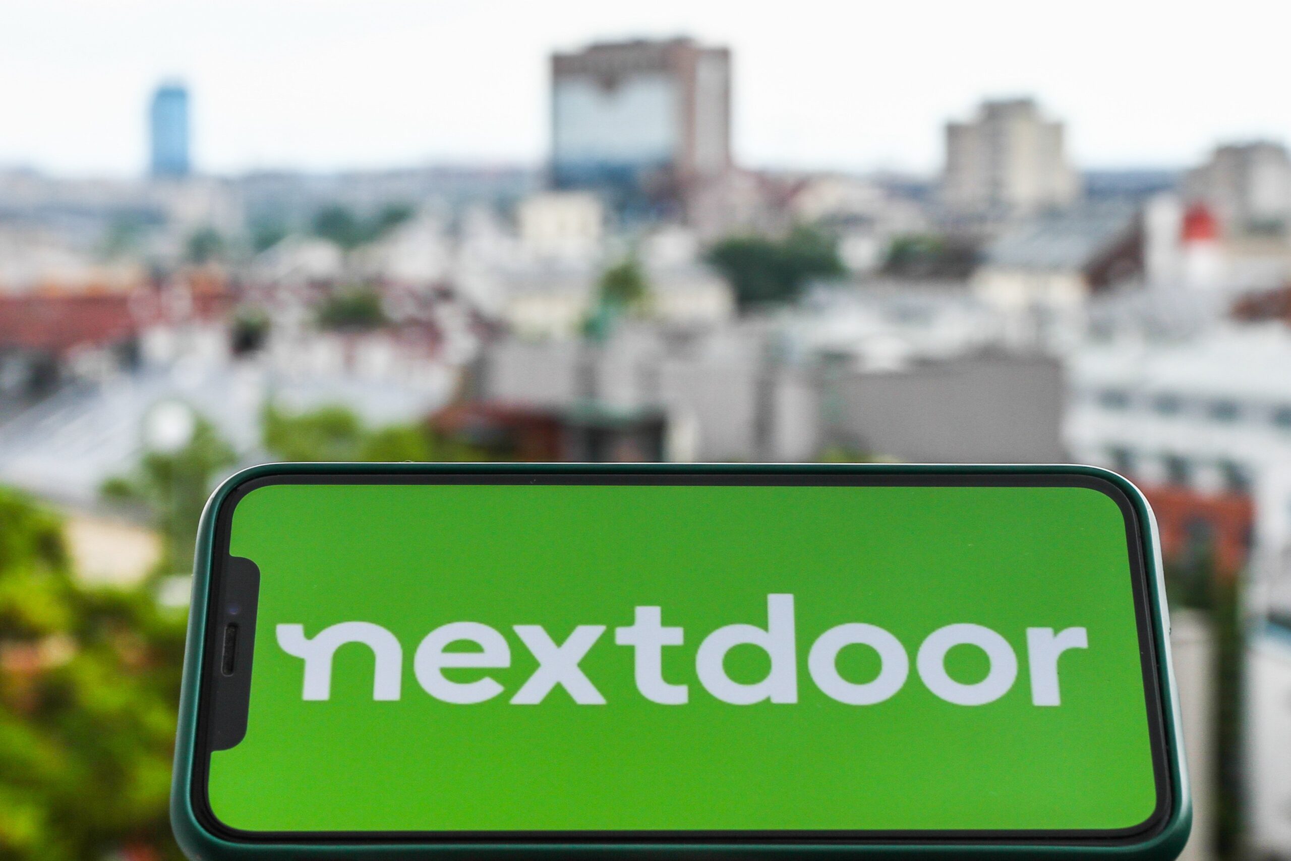 nextdoor app on phone with a cityscape in the background