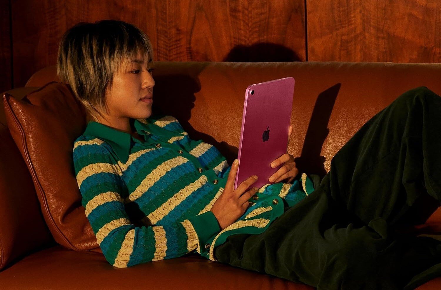 a person looks at a pink apple ipad while laying on a couch
