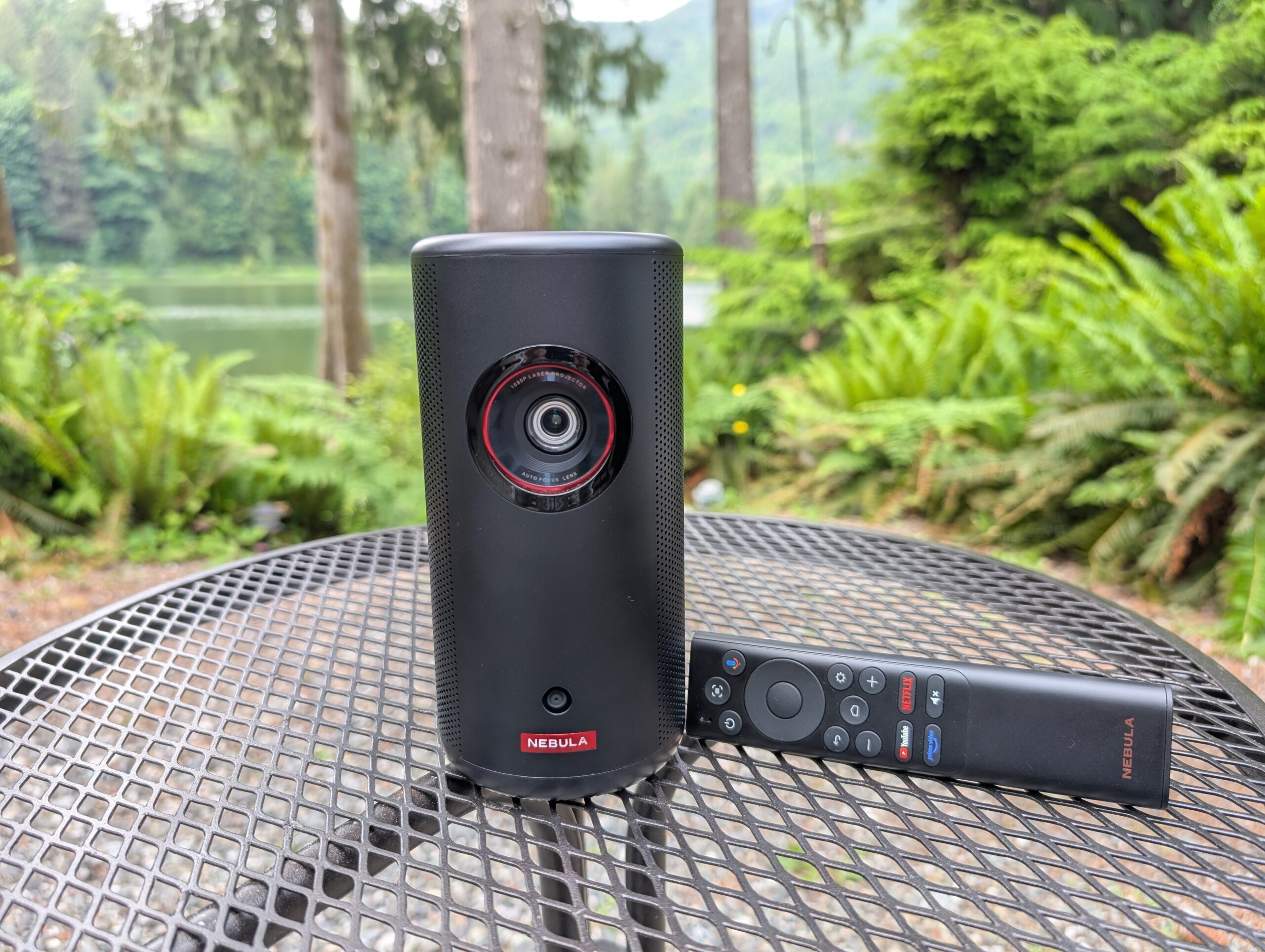 the anker nebula capsule 3 laser projector on a table outside with its included remote control