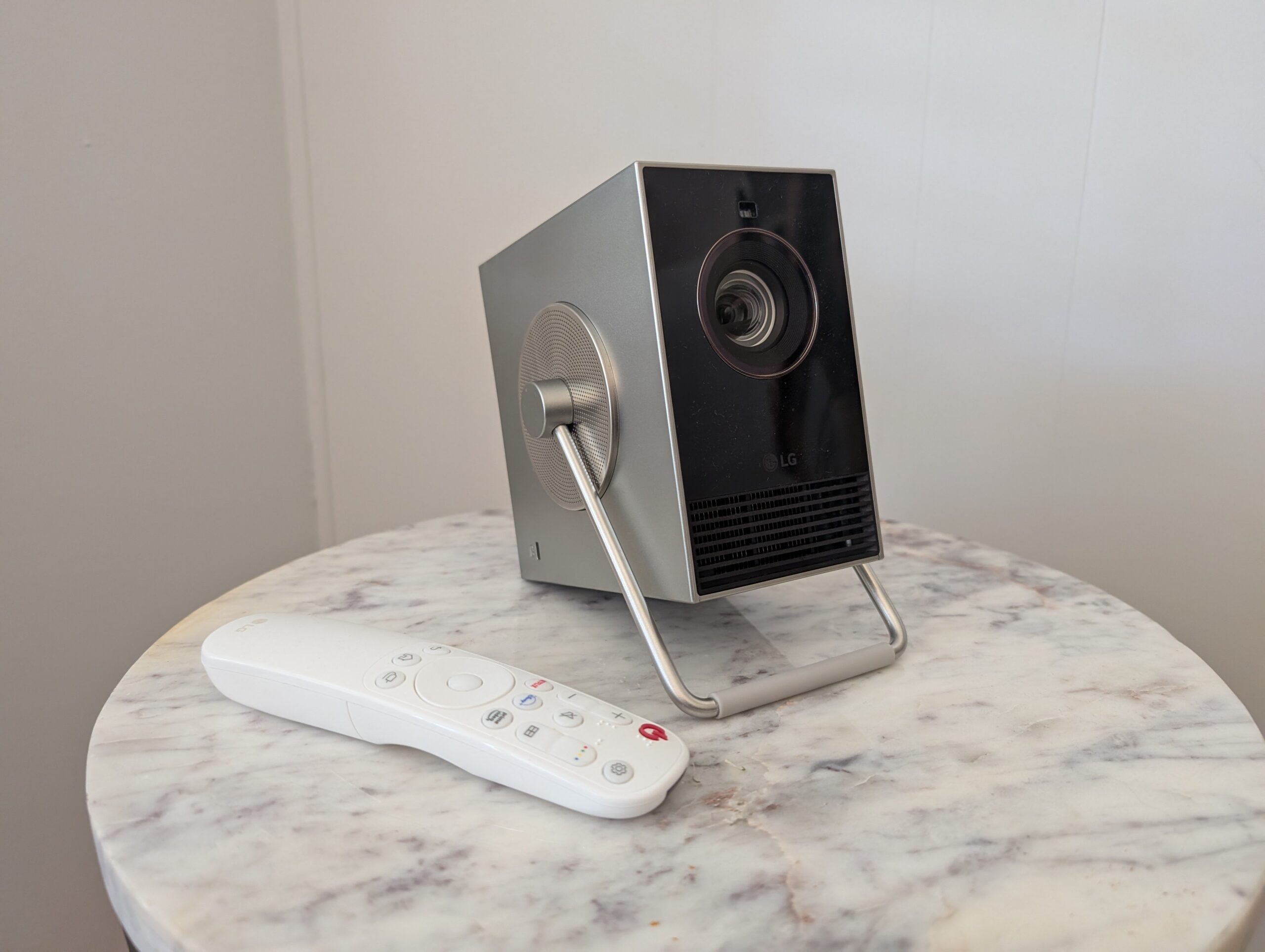 the LG CineBeam Q 4K projector with include remote control sit on a white granite side table