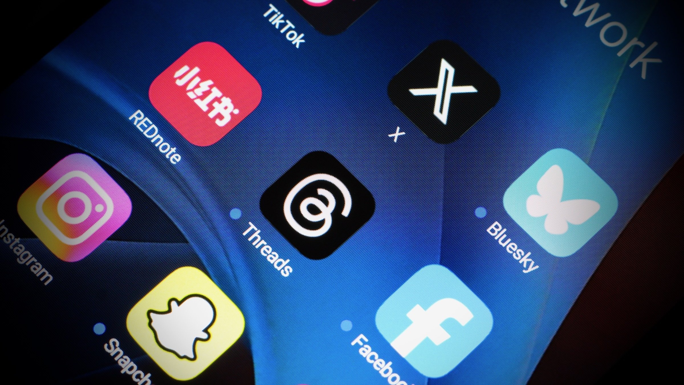 social media app logos seen on iphone screen, with Threads at the center