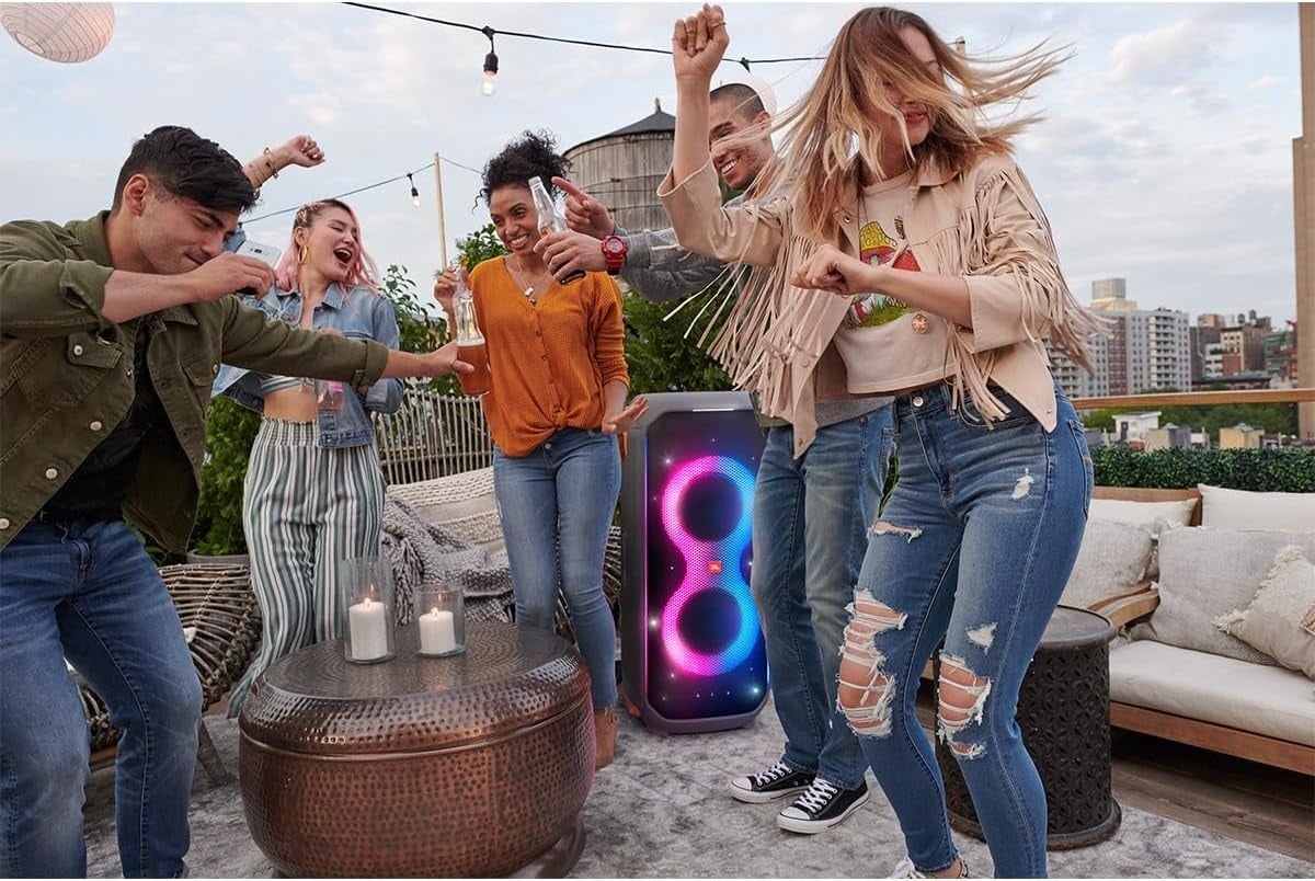 the JBL party box 710 speaker sits on a rooftop in the middle of people dancing