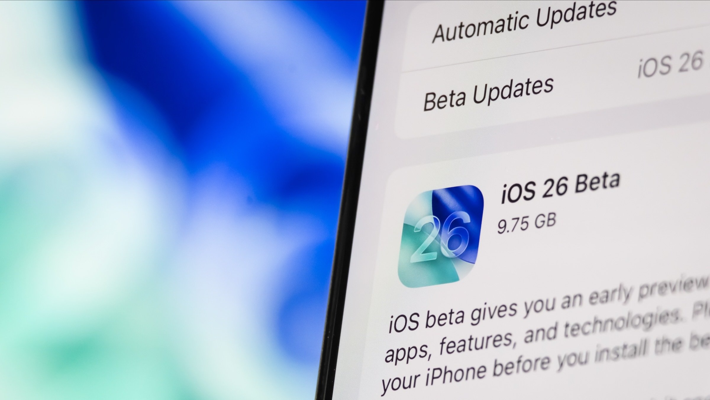 A detailed iOS 26 Beta update description is displayed on an iPhone screen.