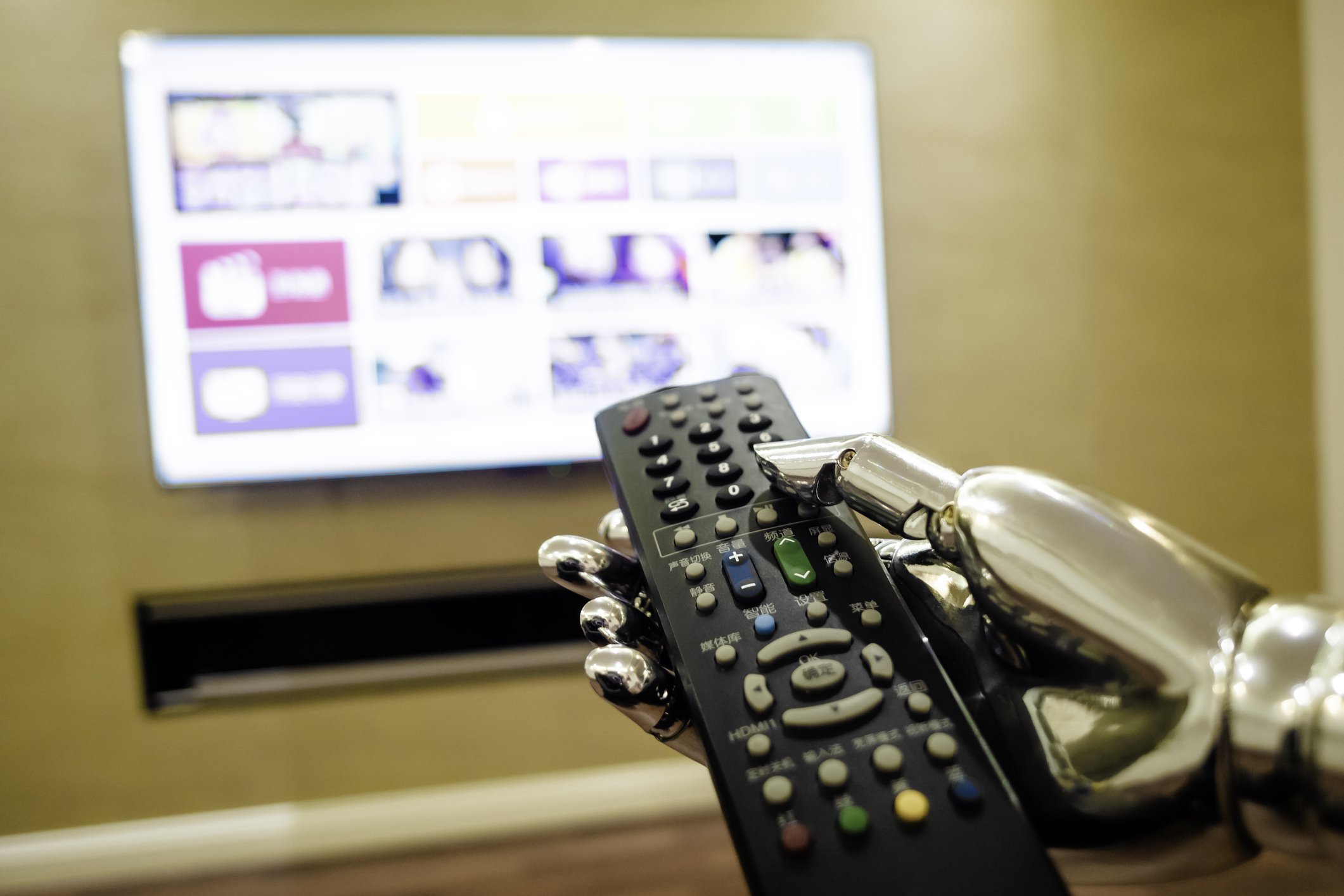 robotic hand holding a remote control pointed at a tv