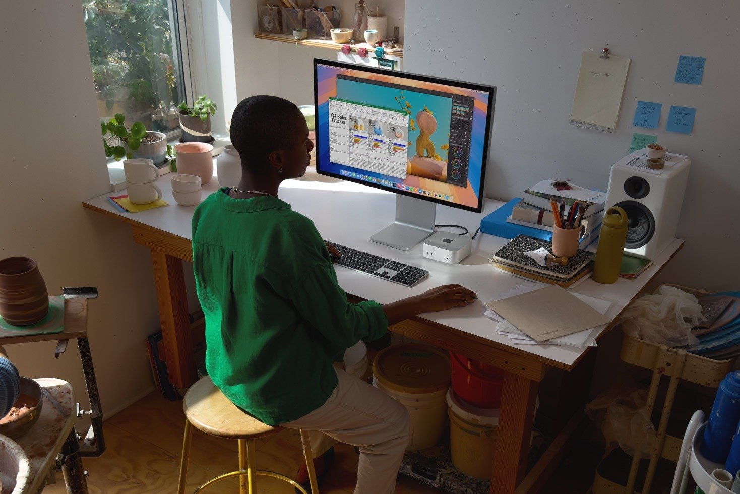 a person sits at a desk with the apple mac mini and a large monitor
