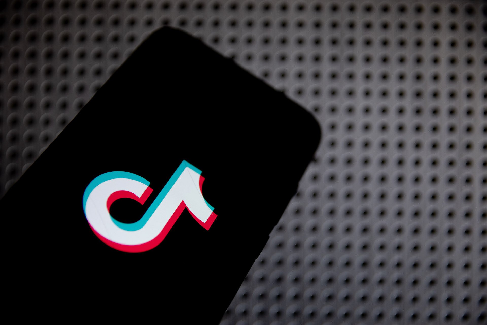 TikTok logo on a phone, against a gray background. 