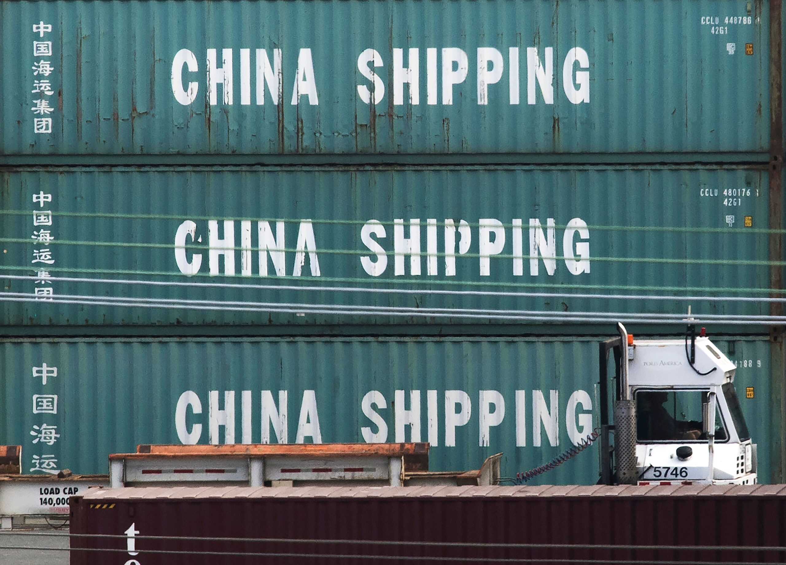 A truck passes by China Shipping containers at the Port of Los Angeles in 2019