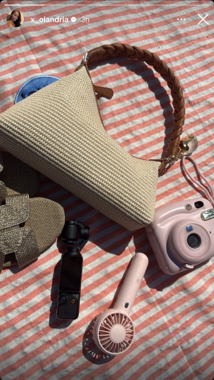 A screenshot of an Instagram story showing a beach bag on a beach towel.