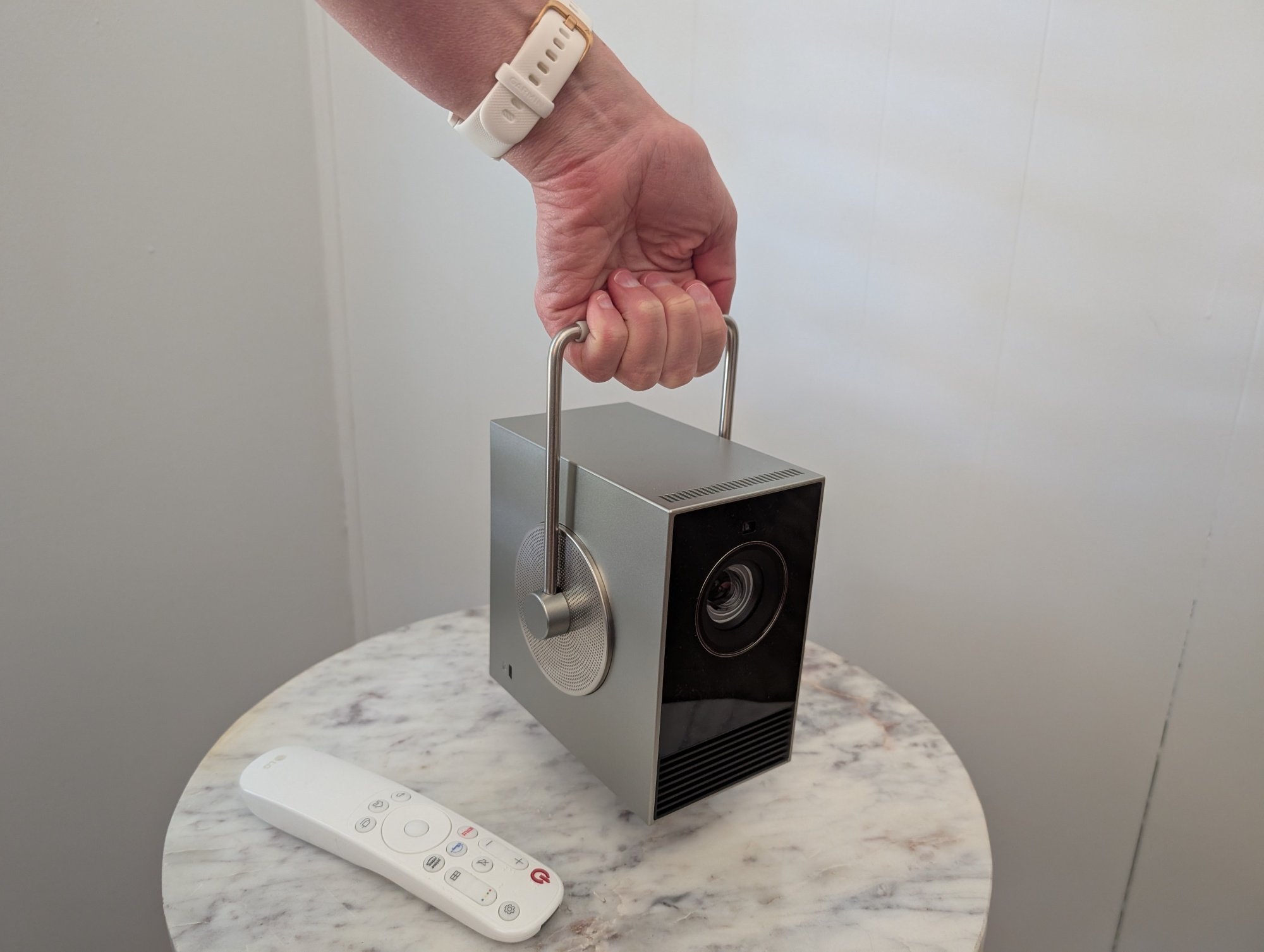 a hand holds the handle on the LG CineBeam Q 4K projector