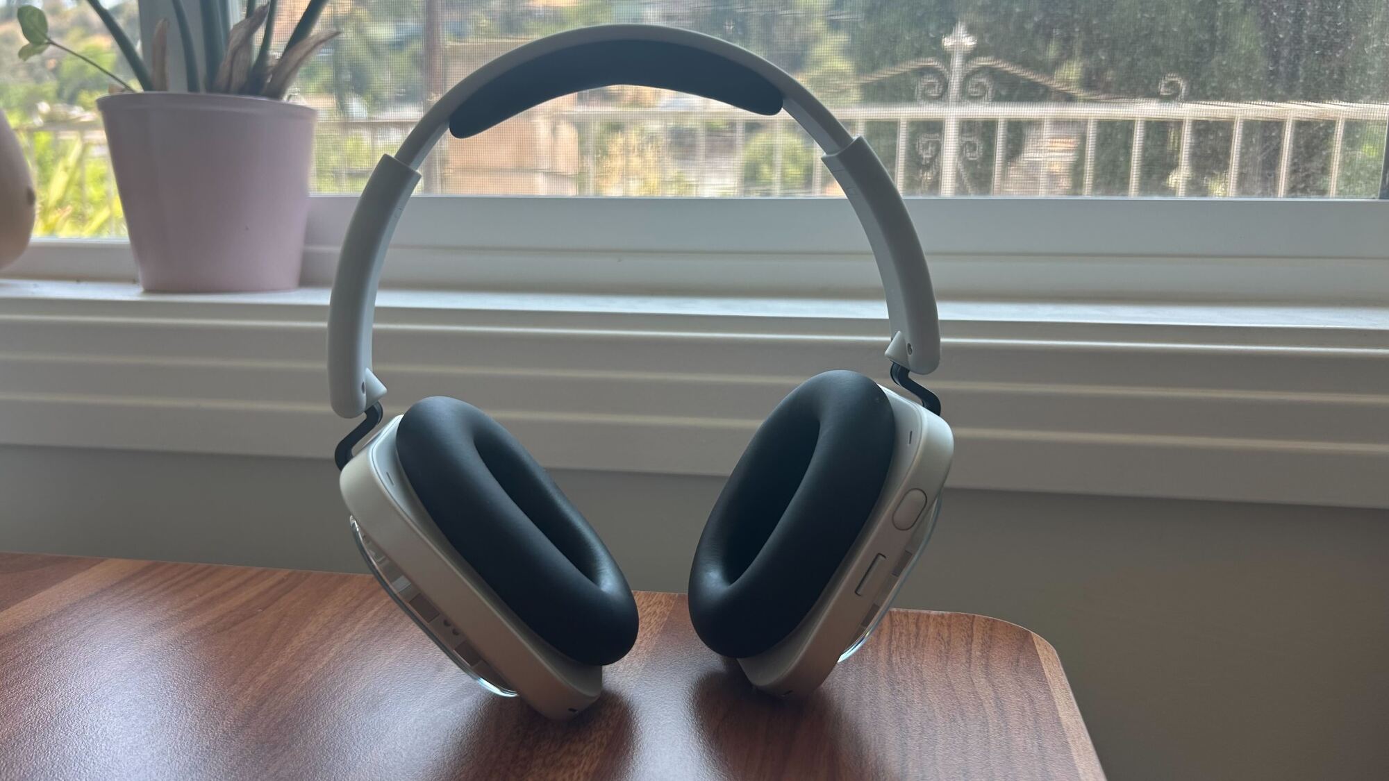 white nothing headphones standing up on desktop in front of window