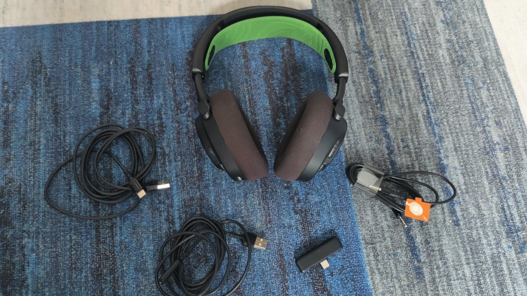 The SteelSeries Arctis Nova 7X Wireless Gaming Headset with the USB-C dongle, USB cable, 3.5mm cable, and USB-C to USB-A adapter cable