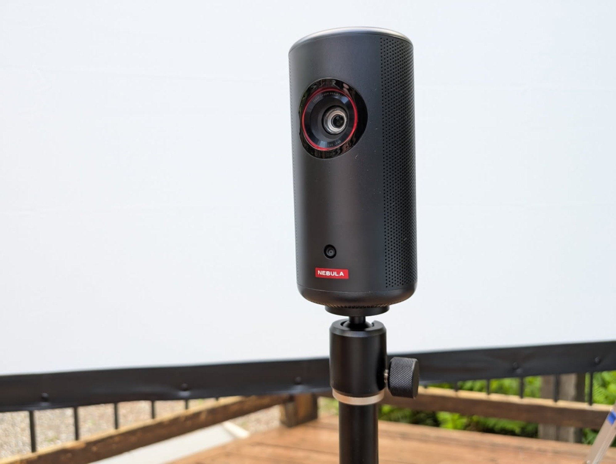 the Anker nebula capsule 3 laser projector on a stand in front of a projector screen