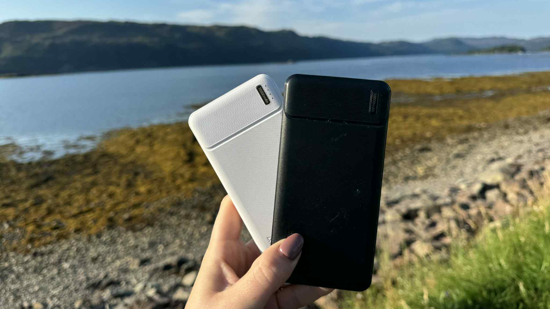 Two portable chargers held up against outdoor setting