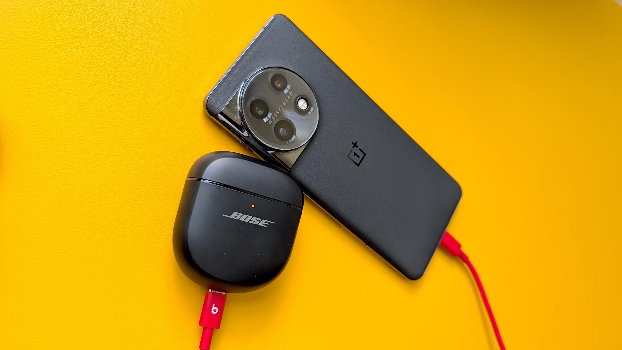 A phone and Bose headphones using reverse charging via a USB-C cable, on a yellow background