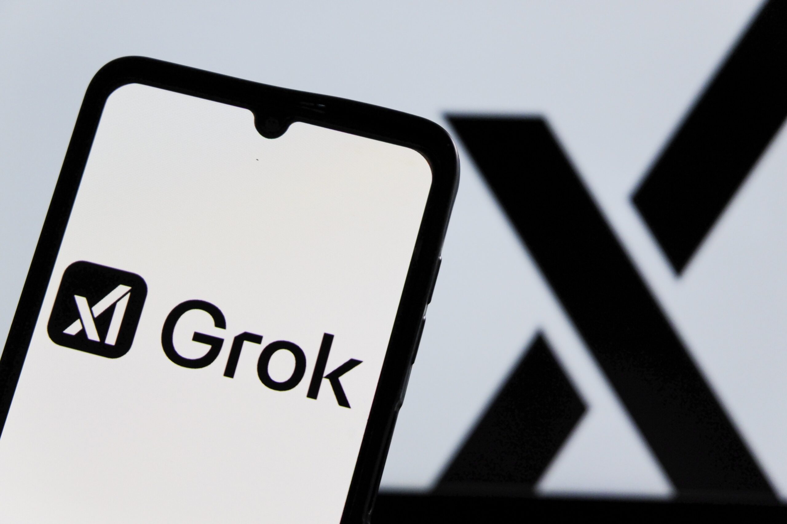 grok and x logos on phone and screen