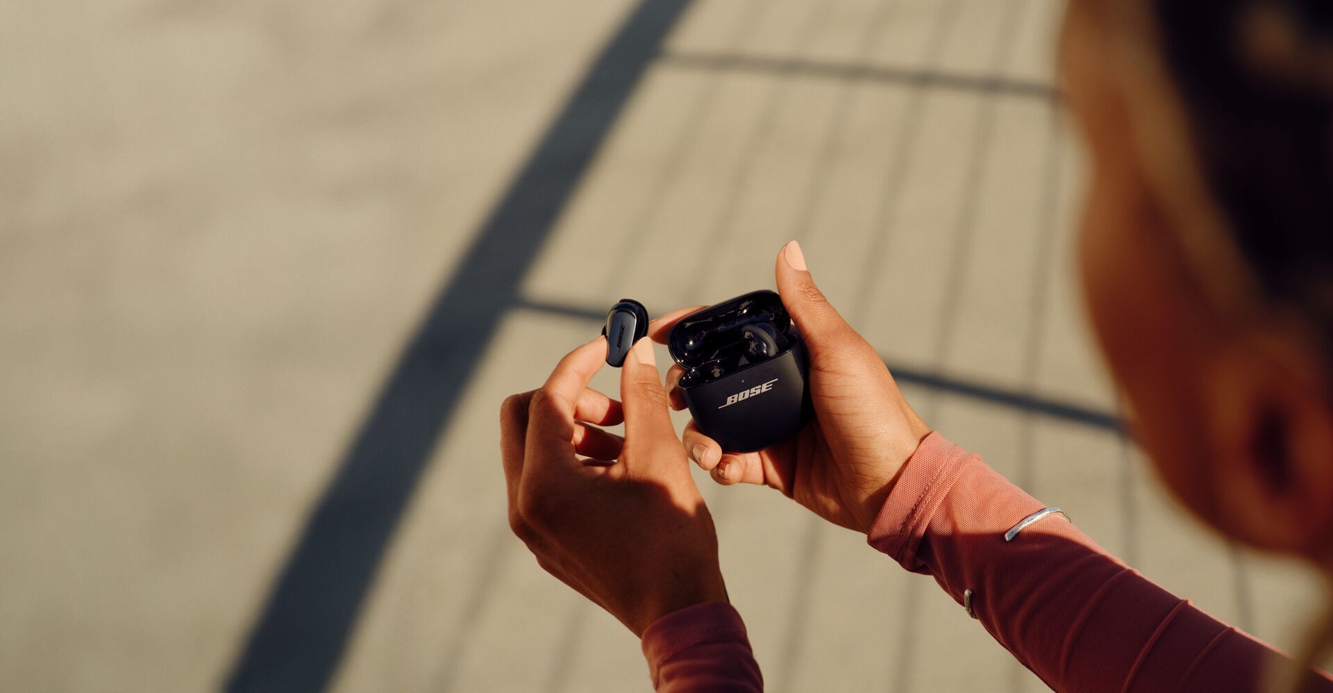 person holding black QC ultra earbuds outside