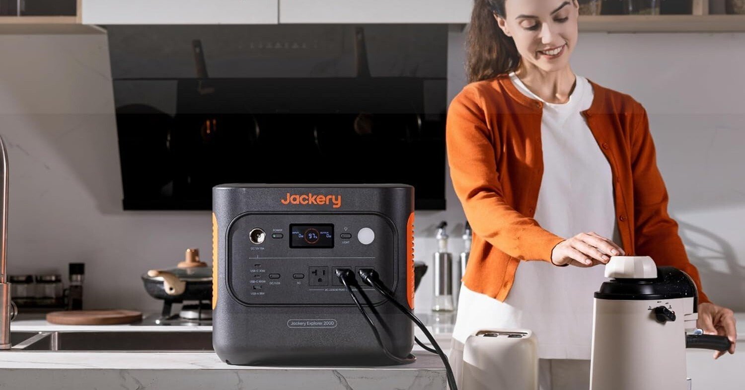 the jackery explorer 2000 v2 sits on the countertop of a white kitchen, powering several appliances.