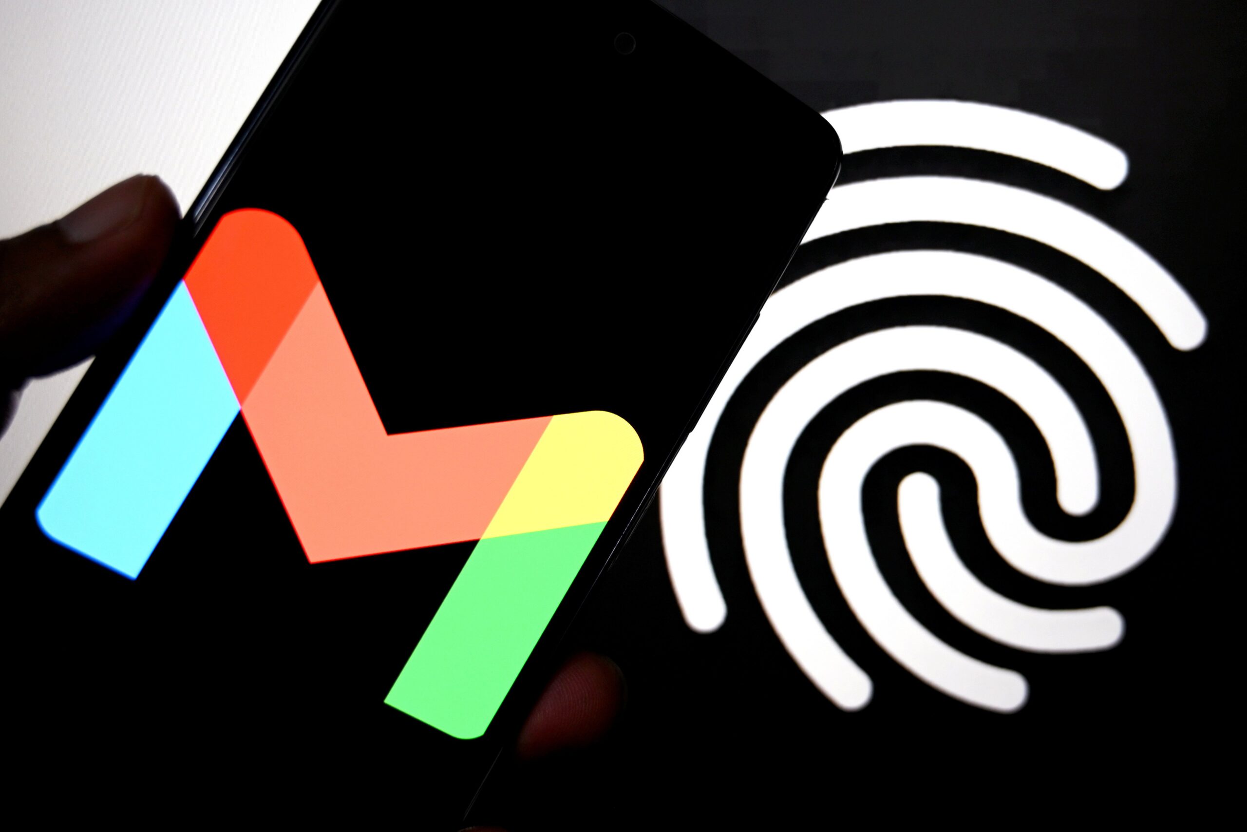 A phone displaying the Gmail logo in front of large Google passkey icon that looks like a fingerprint.