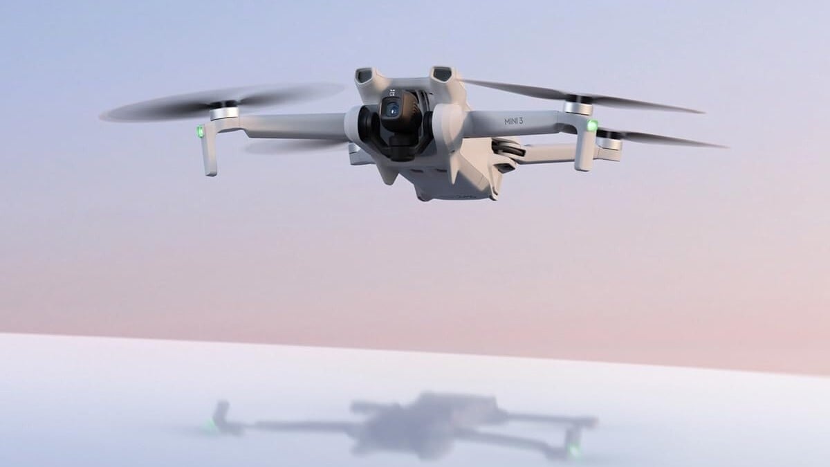 the DJI Mini 3 drone flies in a sunrise sky with blue and pink hues