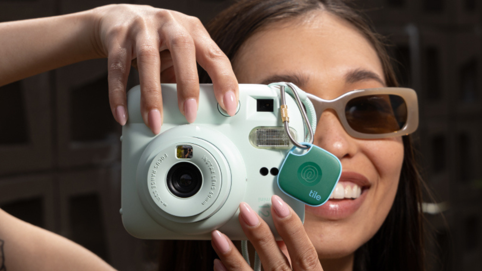 woman snapping a photo with camera with Tile Mate attached 