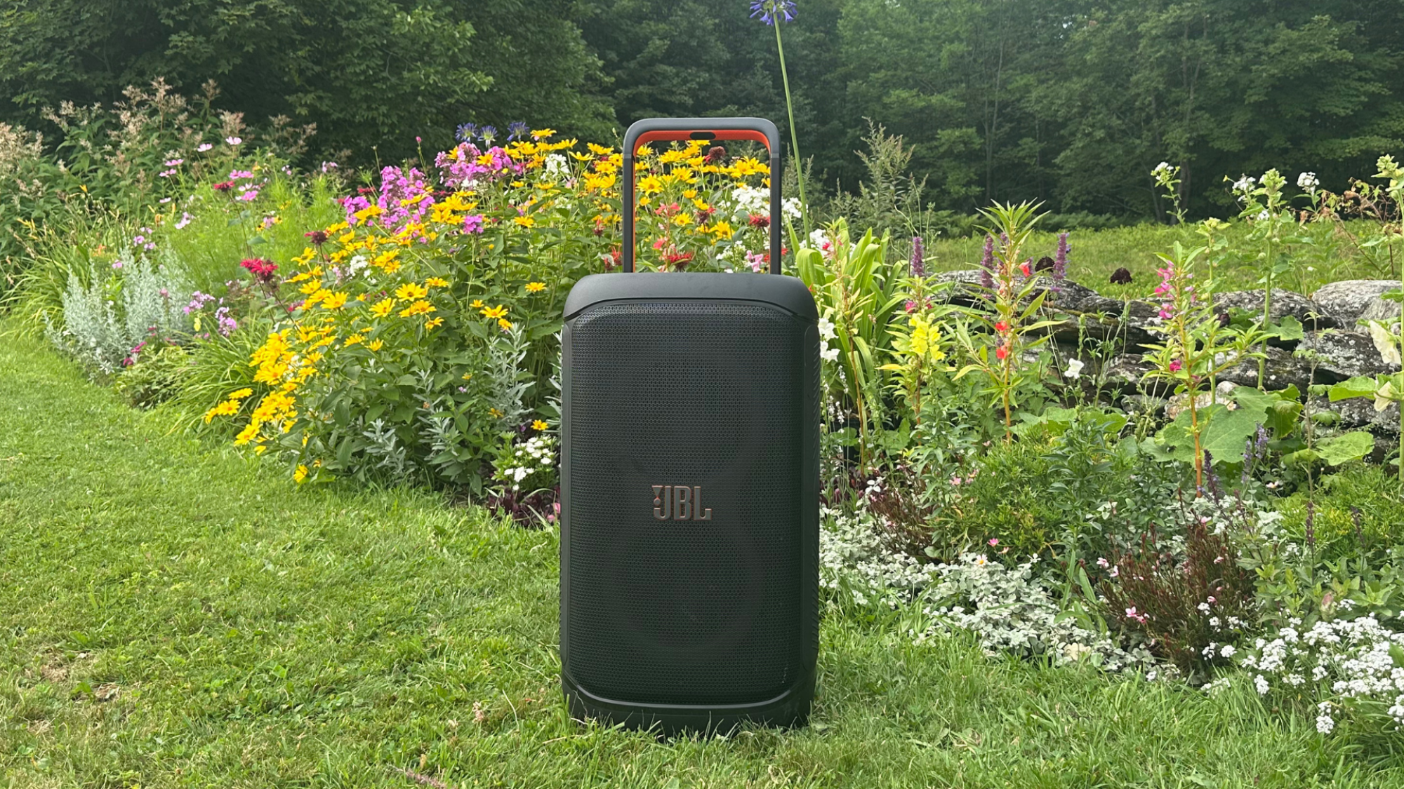 A JBL PartyBox 520 speaker against a garden