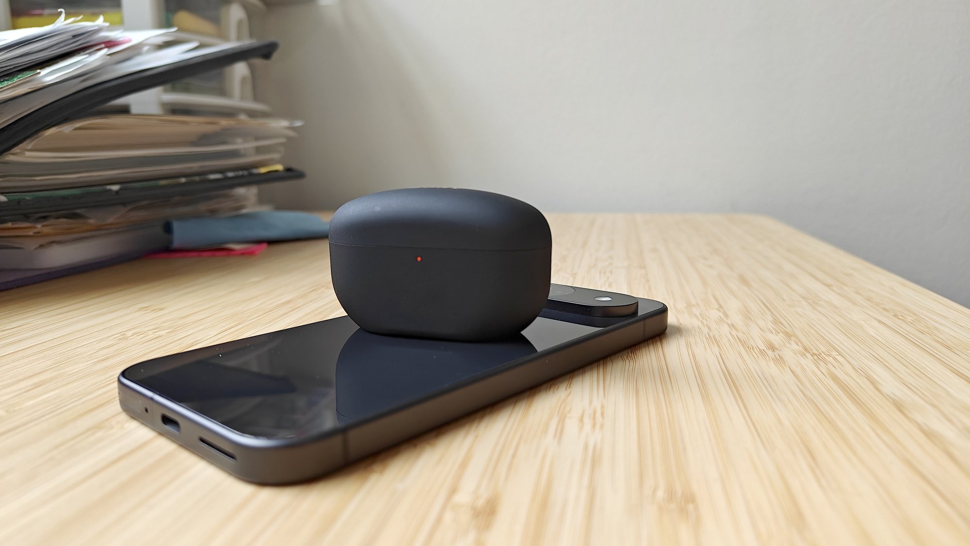 An earbuds case wirelessly charging on top of a phone