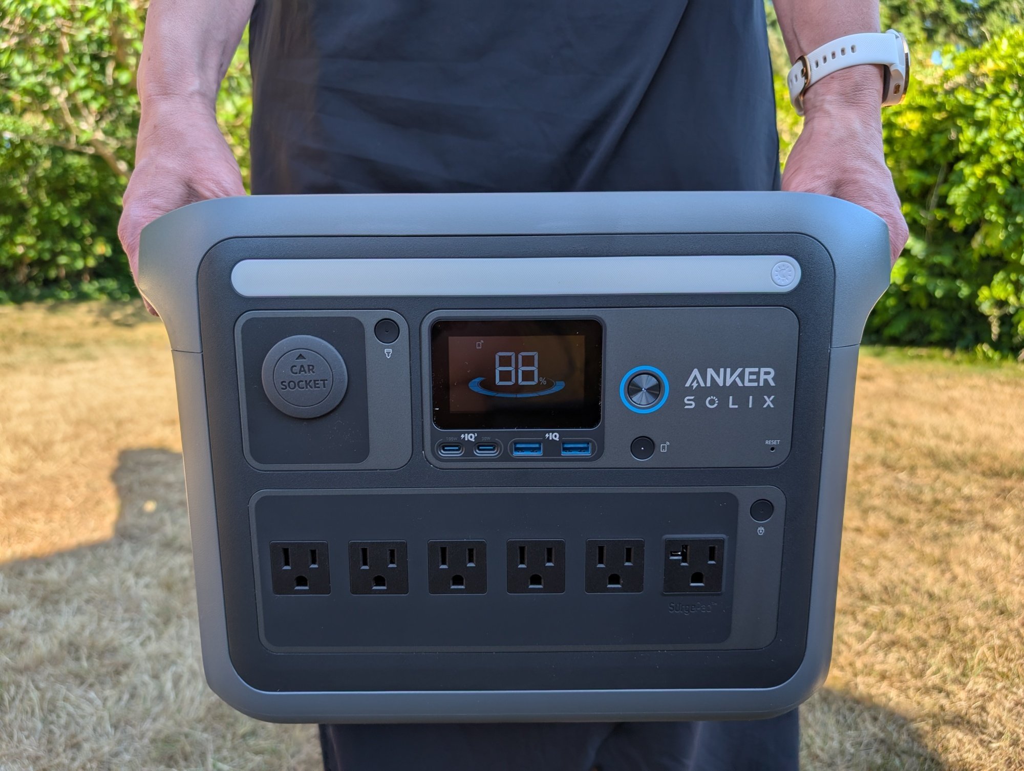 a person holds the anker solix c1000 portable power station in front of them while wearing a black dress.