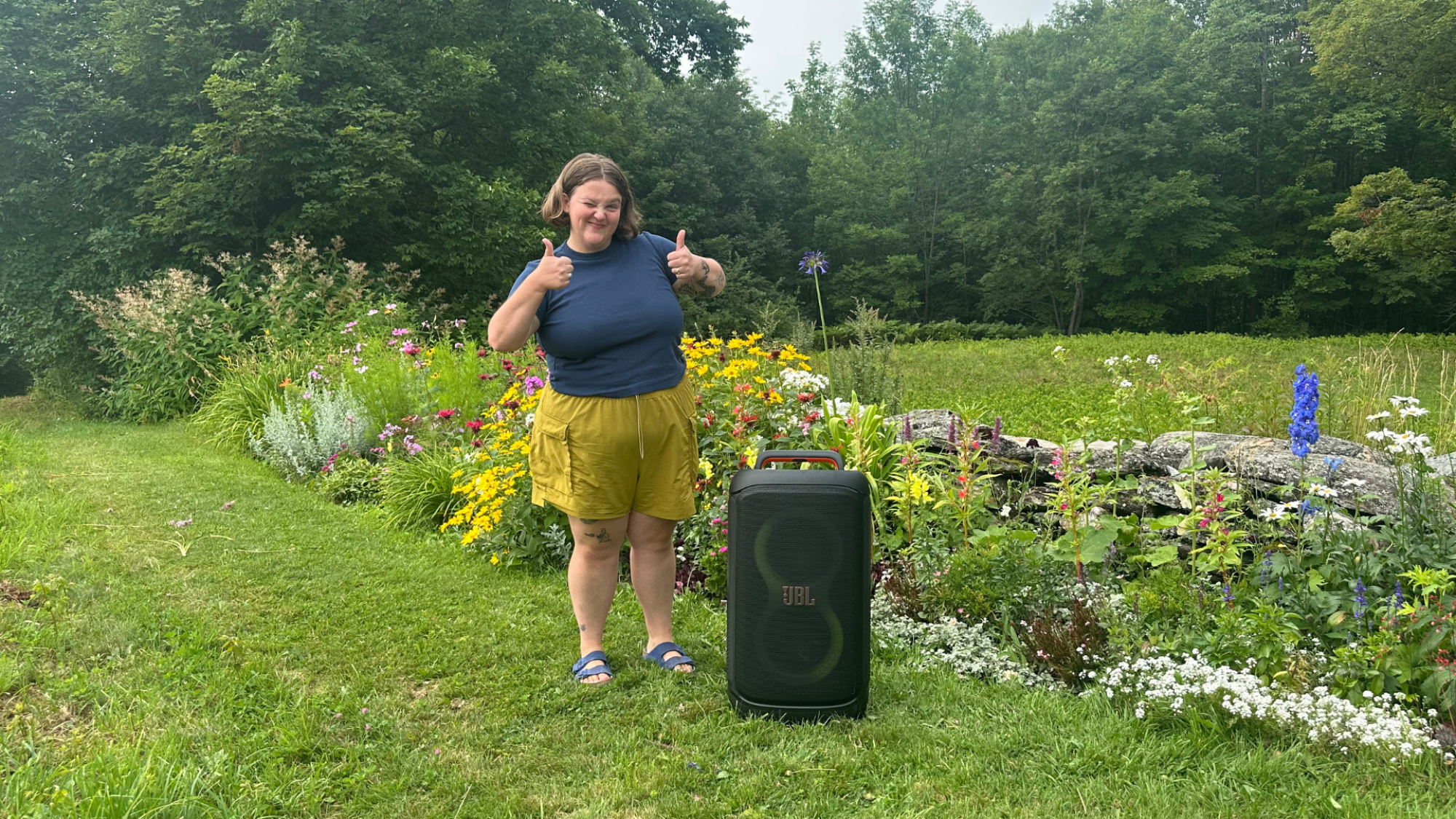 A person giving two thumbs up to the camera standing next to the JBL PartyBox 520 speaker.