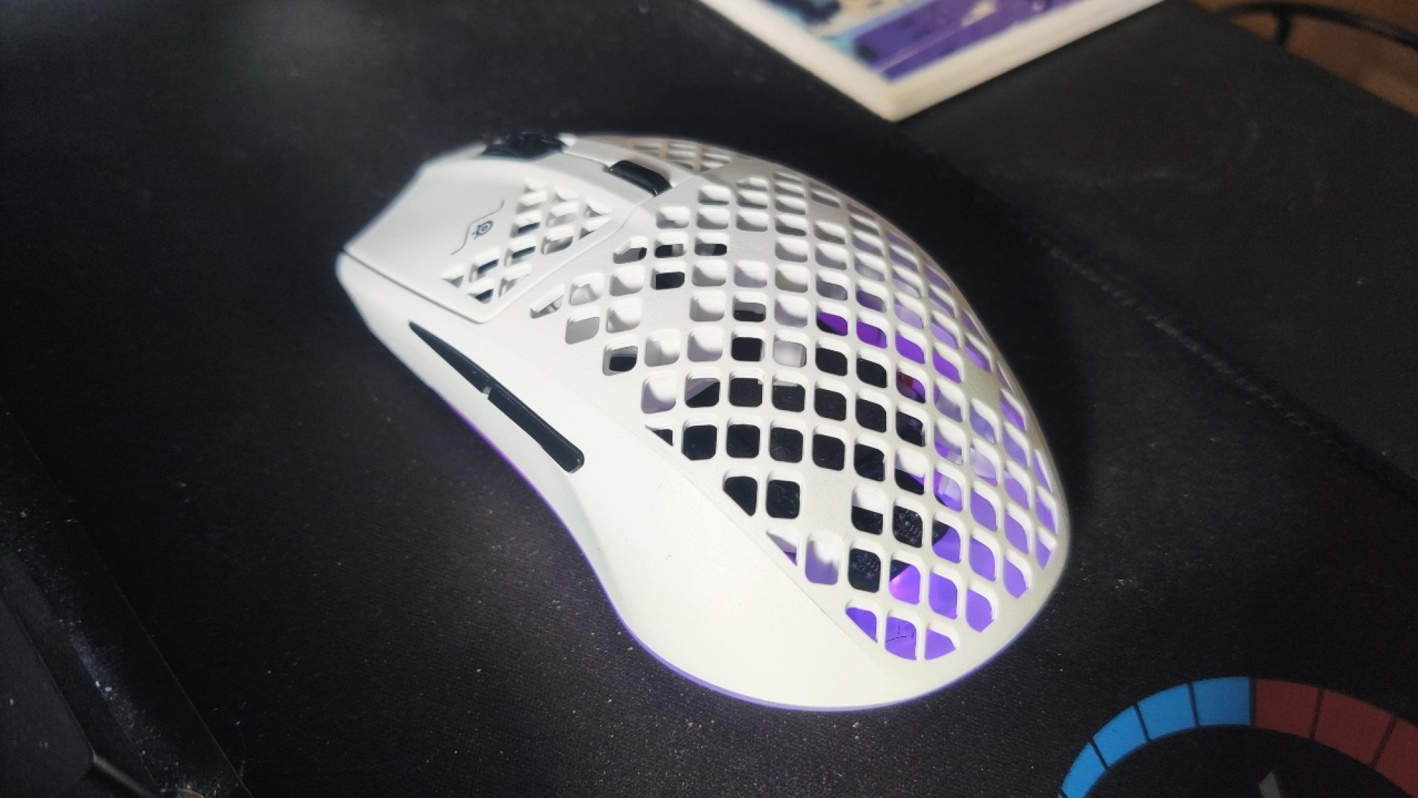 The SteelSeries Aerox 3 Wireless gaming mouse on a black mouse mat