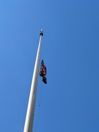 A flag pole in front of a blue sky