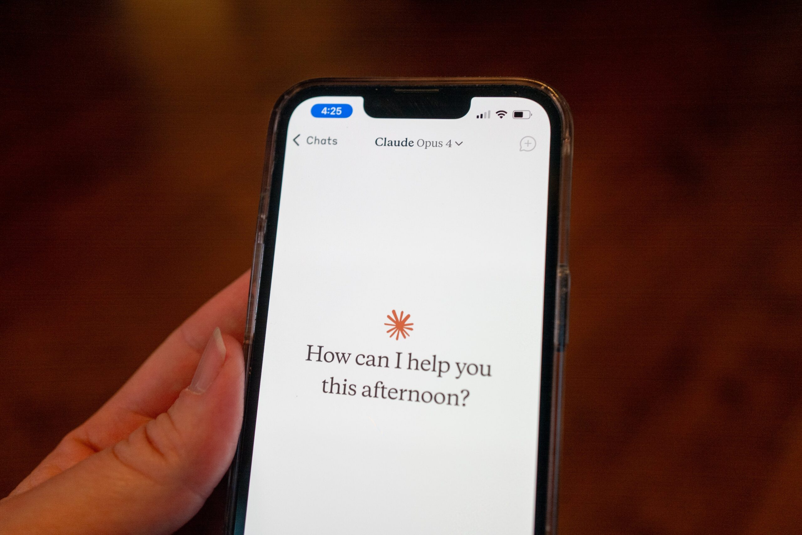 phone with claude app on screen with the question, 'how can i help you this afternoon?'