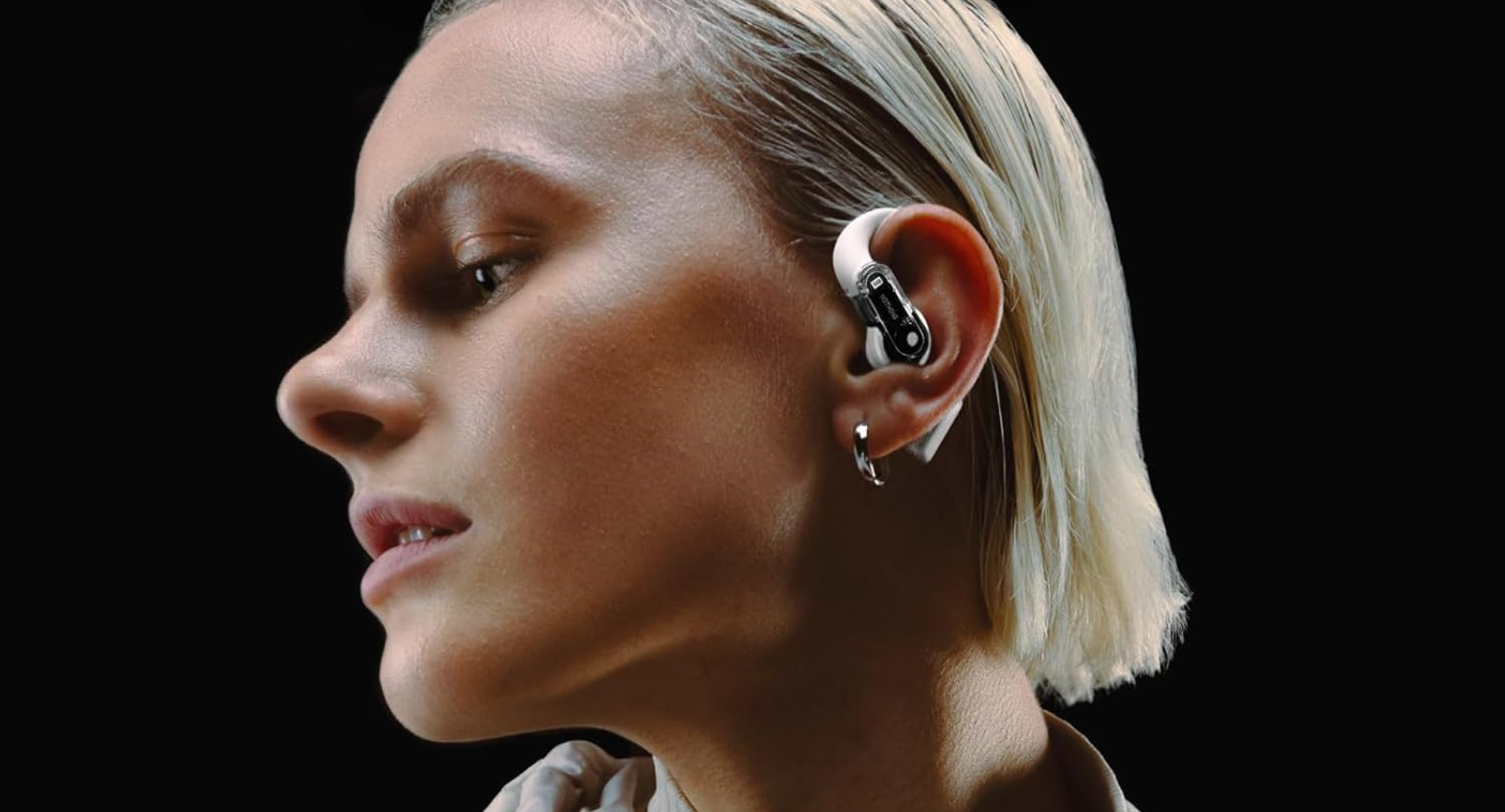 A woman with platinum blonde hair wearing the Nothing Ear open open-ear earbuds.