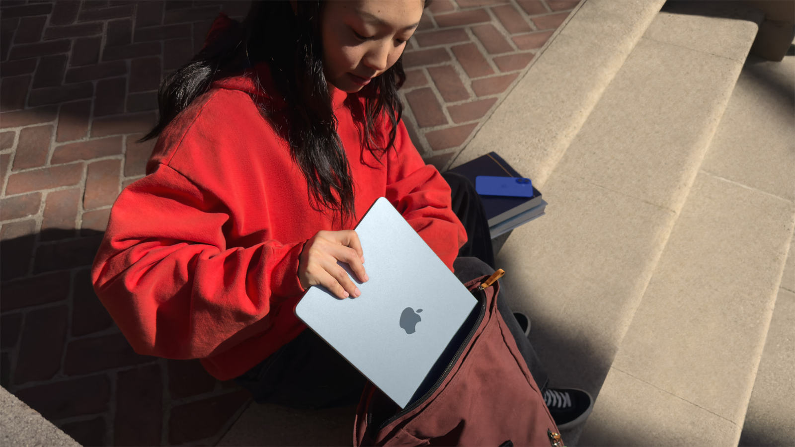  a girl putting an m4 apple macbook air into a backpack