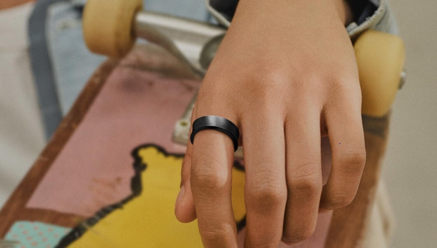 a person wears the samsung galaxy ring while their hand is slung over a skateboard