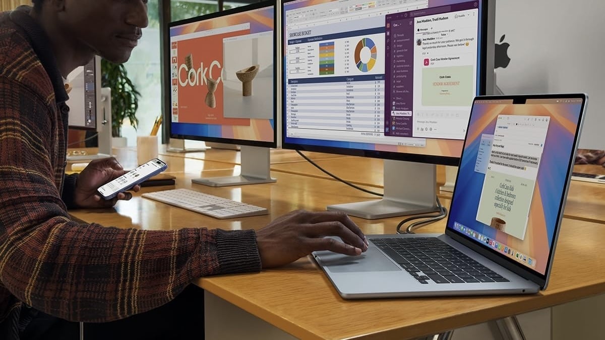 person working on desk with macbook air connected to two displays